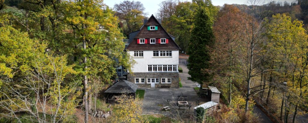 Luftaufnahme vom CVJM Haus Köttingen mit Blick auf die Terasse mit Feuerstelle.